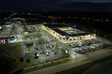 Aerial night view of many cars parked on parking lot with lines and markings for parking places and directions. Place for vehicles in front of a grocery mall store