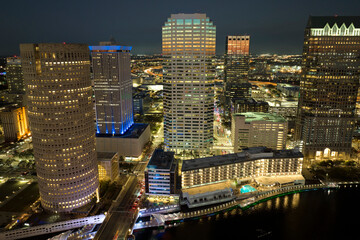 Fototapeta premium Aerial view of downtown district of Tampa city in Florida, USA. Brightly illuminated high skyscraper buildings, pedestrian riverwalk and moving traffic in modern american midtown