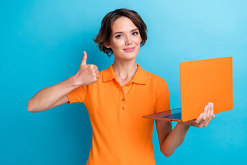 Photo of cool positive girl dressed orange polo showing thumb up texting modern device isolated...