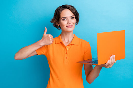Photo of cool positive girl dressed orange polo showing thumb up texting modern device isolated blue color background