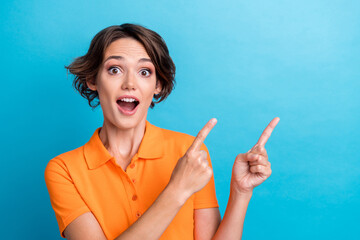 Photo of charming impressed girl dressed orange polo showing two fingers empty space isolated blue...