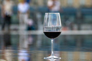 Tasting of Bordeaux blended red wine with wine city Bordeaux on background, left bank of Gironde Estuary, France. Glass of red French wine.