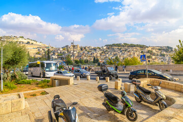 Obraz premium Residential buildings can be seen from alongside the busy streets full of pedestrian and traffic alongside the Temple of the Mount in the historic old city of Jerusalem, Israel.