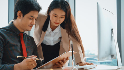 Two business people talk project strategy at office meeting room. Businessman discuss project planning with colleague at modern workplace while having conversation and advice on financial report. Jivy