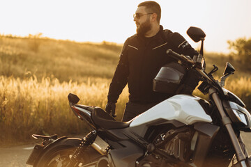 Man biker standing by his bike holding his helmet