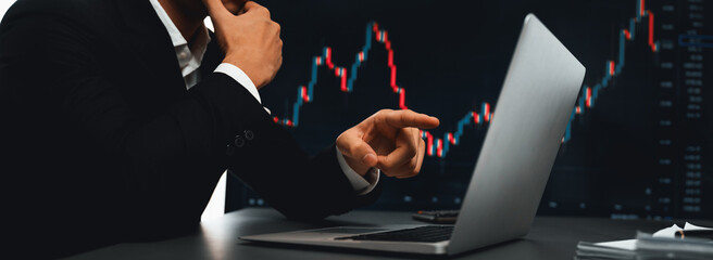 Stock trading investor finger pointing on dynamic financial data graph on monitor. Businessman or broker with analytic thinking analyzing data for stock market exchange trading company. Trailblazing