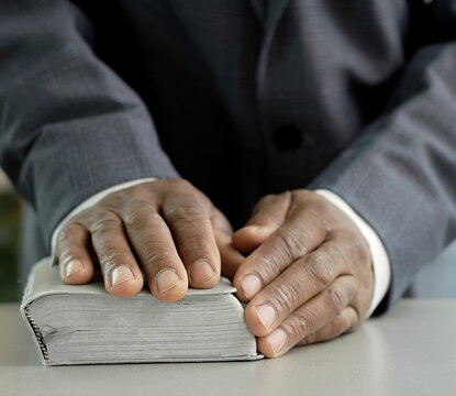black man praying to god with bible with background with people stock image stock photo