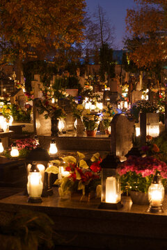 Catholic cemetery at night with lit candles standing on the tombstones. Memory of deceased loved ones.