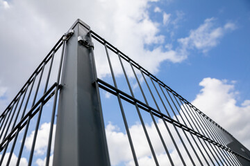 Close-up view of a steel fence post with fence panels attached.