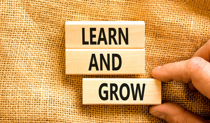 Learn and grow symbol. Concept word Learn And Grow on beautiful wooden block. Businessman hand....