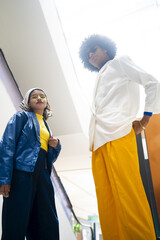 low angle of an fashionable afro mexican man and young woman looking down to the camera