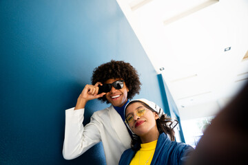 Young woman takes a selfie with her afro mexican man friend with sunglasses having fun