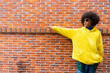 fashionable afro mexican man with cool attitude is pointing copy space