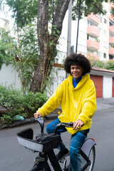 man afro mexican smiles to the camera while is riding on a rented bicycle on the streets of Mexico City