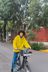 man afro mexican going on the street on a rented bicycle smiling to the vertical camera in Mexico City