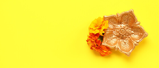 Diya lamp and marigold flowers on yellow background with space for text. Celebration of Divaly (Indian Festival of Lights)