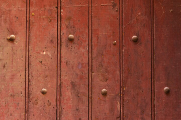 Texture of a wooden board painted red with rivets.