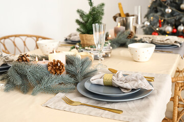 Christmas table setting with wreathes, burning candles and pine cones