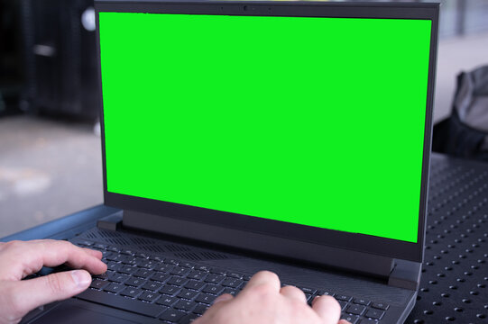 Rear view man freelance working in cafe, using a laptop computer with a green screen on the monitor. Concept remote work, freelance, working on a laptop computer or net-book.