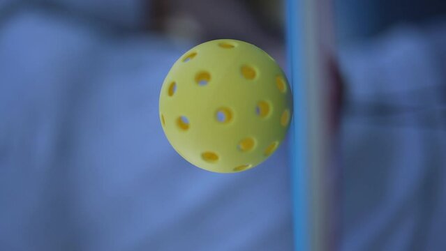 Ball spinning on a pickleball racket in pickler's hand in slow motion