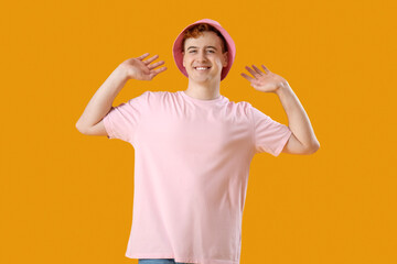 Young man in t-shirt and hat on yellow background