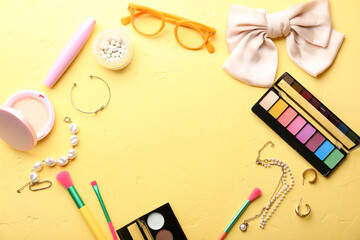 Frame made of stylish female accessories and cosmetics on yellow background