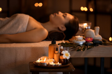 Spa composition with burning candles and plumeria flowers in dark salon, closeup