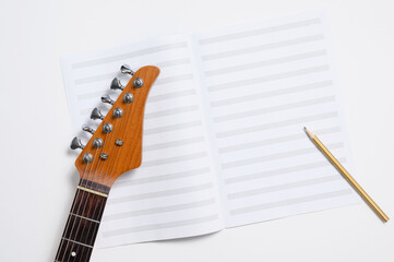 Electric guitar neck and new music book. Music lessons concept.