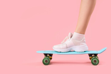 Young woman with skateboard on pink background, closeup