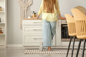 Woman on striped carpet in light kitchen, back view
