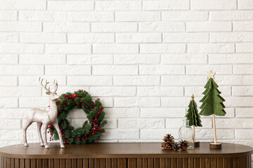Wooden cabinet with Christmas decor and deer near white brick wall