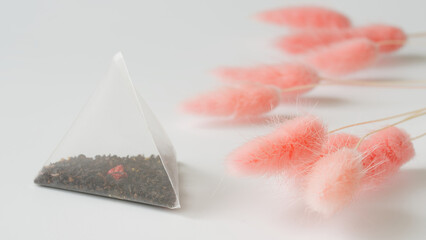 Nylon white pyramid tea bag with black tea, with the addition of fruits and berries, lies on a...