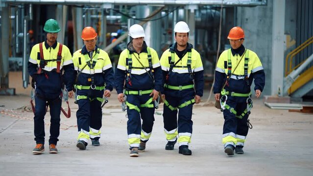 Team industrial workers in protective uniform helmet going at manufacture refinery workshop
