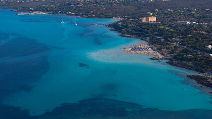 Aerial view of La Pelosa beach at sunny summer day. Stintino, Sardinia island, Italy. Drone view of sandy beach, playing people, clear blue sea.