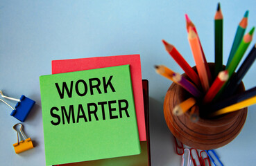 WORK SMARTER - words on a green sheet for notes on the background of pencils and paper clips