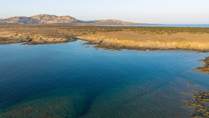 Aerial photo of the island of Isola Piana near Stintino and the beach of Spiaggia La Pelosa. Mountainous island, blue water and clear sky. Northwest part of Sardinia, Sassari Province, Italy. 