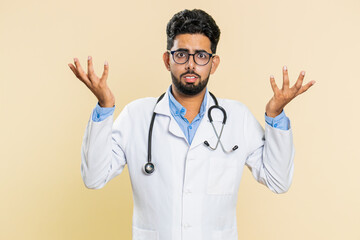 What. Why. Confused Indian doctor cardiologist man raising hands in indignant expression asking...