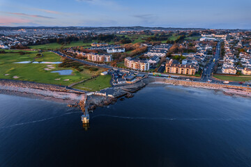 Aerial view on Salthill Promenade in Galway city, Ireland. Popular travel area. Black rock diving board and beach. City landmark and swimming place. Sunset blue hour. Rich saturated color.