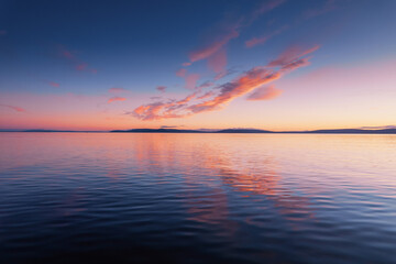 Blue cloudy sky over Burren mountains and reflection in dark water of Galway bay, Ireland. Blue hour nature scene. Nobody. Aerial view.