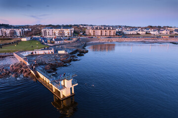 Fototapeta premium Blackrock diving board in Salthill area of Galway city, Ireland. Famous city landmark. Blue hour. Rich saturated color. Aerial view.