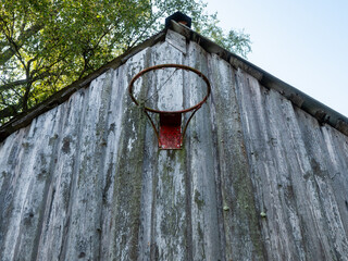 Old rusty basketball hoop mounted on a wooden wall of a barn of a farm. Popular sport. Practice and develop skill in tough rough conditions.