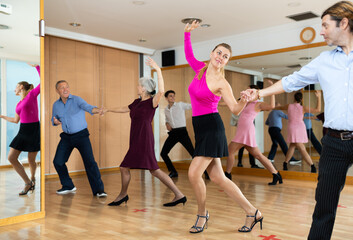 Portrait of smiling young woman dancing upbeat vigorous partner swing during group training in dance studio