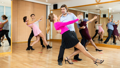 young woman coach dancing waltz with partner at group ballroom dancing class
