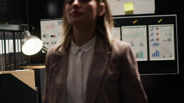 Caucasian female detective inspector closes laptop and folder leaving the office. Policewoman standing and exiting the evidence room after gathering information to solve criminal investigation.