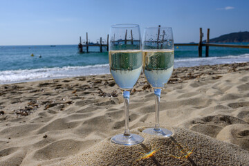 Summer time in Provence, two glasses of cold champagne cremant sparkling wine on famous Pampelonne sandy beach near Saint-Tropez in sunny day, Var department, France