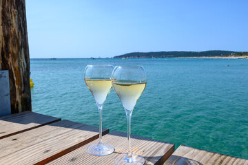 Summer time in Provence, two glasses of cold champagne cremant sparkling wine on famous Pampelonne sandy beach near Saint-Tropez in sunny day, Var department, France - obrazy, fototapety, plakaty