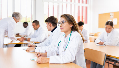 Portrait of doctors different age who writing exercises at lesson in university
