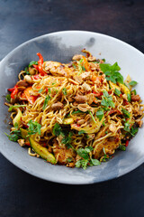 Traditionelles thailändisches Pad Mama mit Instand Nudeln, Hühnchen und Gemüse serviert als close-up auf einem Design Teller mit Textfreiraum