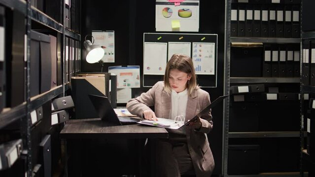 Law officer entering room, using laptop to analyze clues and perform comprehensive investigation. Office space is furnished with equipment for criminal analysis and crammed with files and folders.