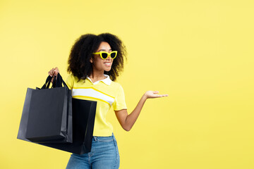 Beautiful smiling curly haired African American woman wearing stylish sunglasses holding black...